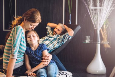 Arkalarındaki kızını sarılma anne olan babası döşeme kanepe.