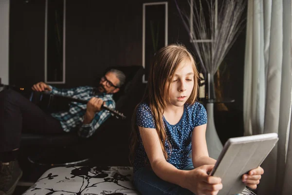 Menina Usando Tablet Sala Estar Enquanto Pai Deitado Sofá Tocando — Fotografia de Stock