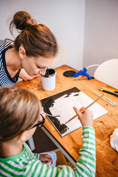 Child painting on canvas during art class with teacher