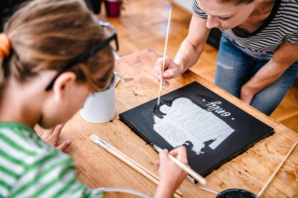 Art teacher helping a student with her painting during art class