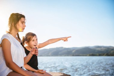 İskelede oturup ve işaret eden iki kız 