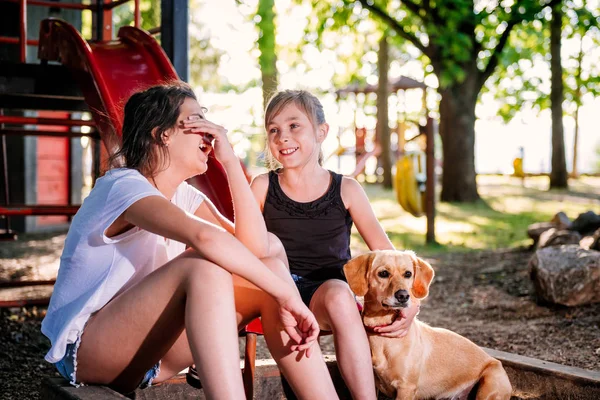 Две Девушки Сидят Парке Смеются Маленькая Жёлтая Собака — стоковое фото