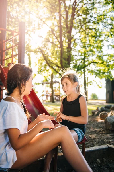 Dos Chicas Jóvenes Sentadas Parque Infantil Hablando —  Fotos de Stock