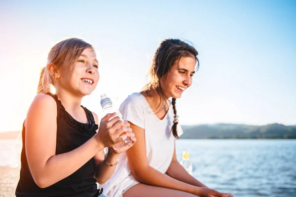 Δύο Κορίτσια Κάθονται Δίπλα Στη Θάλασσα Στην Αποβάθρα Και Γελά — Φωτογραφία Αρχείου