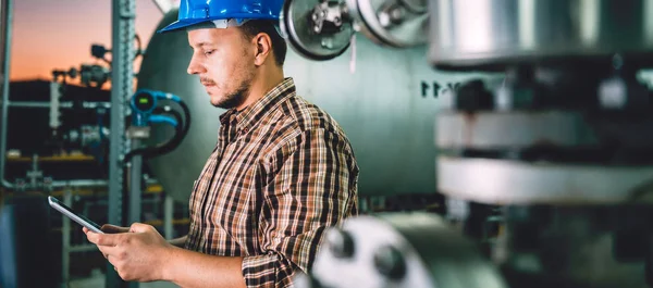 Tablet Doğalgaz tesis işleme kullanarak mavi kask giyen adam