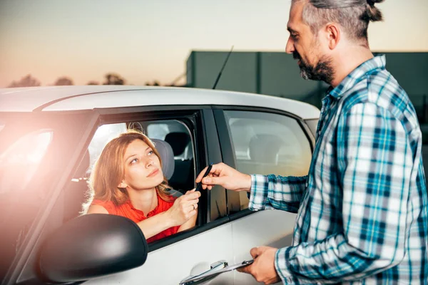 Woman sitting in the car and signing car rental agreement