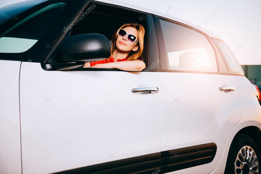 Young woman posing in her new white car