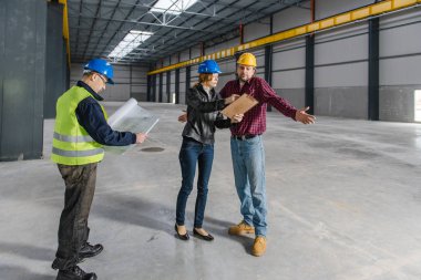 Denetim raporu büyük endüstriyel salonda yapma ve inşaat işçileri ile konuşurken sitesine Müfettiş
