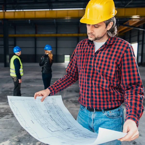 Bauarbeiter Mit Schutzhelm Liest Baupläne — Stockfoto