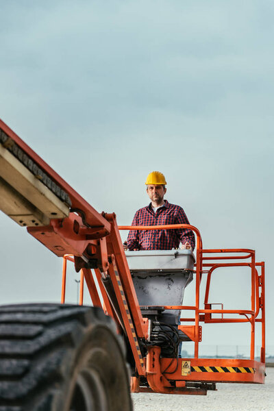 Operator In Safety Helmet and red square shirt controlling Straight Boom Lift