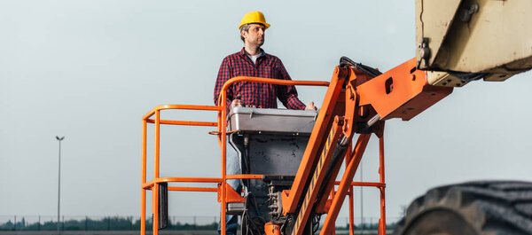 Operator In Safety Helmet and red square shirt controlling Straight Boom Lift