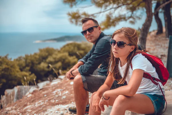Apa és lánya ülnek egy sziklán, miután túráztak. — Stock Fotó