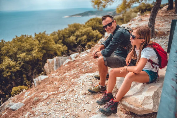 Apa és lánya ülnek egy sziklán, miután túráztak. — Stock Fotó
