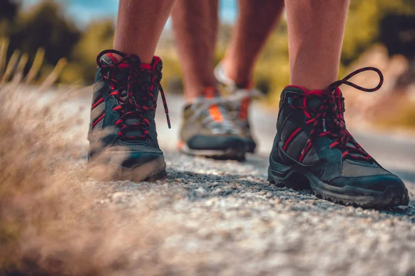 Botas de caminhantes em uma estrada de montanha — Fotografia de Stock