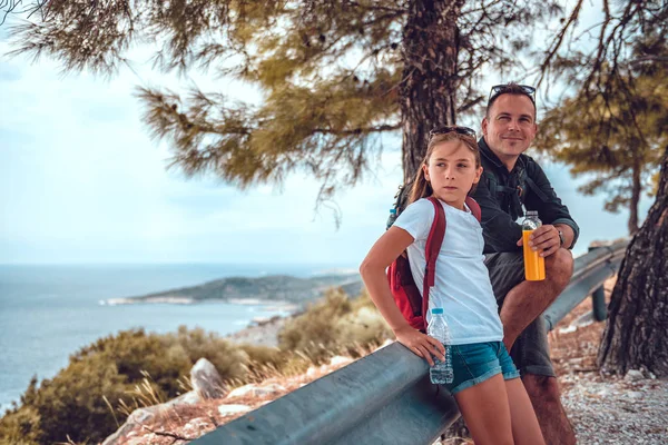 Father and daughter resting after hiking along sea coastline Stock Photo