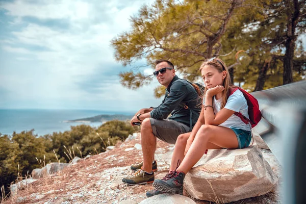 Far og datter sidder på en klippe efter vandreture Royaltyfrie stock-fotos