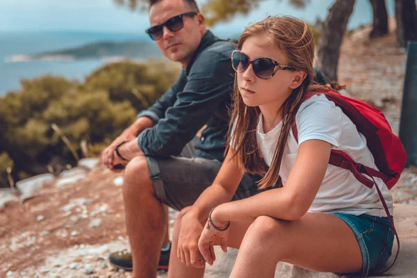 Father and daughter sitting on a rock after hiking Stock Photo