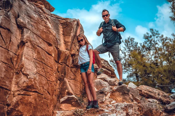 Apa és lánya leereszkednek egy szikláról. Stock Kép