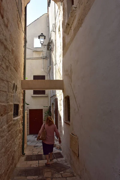 İtalya, Puglia bölgesi, 18/08/2017, Polignano, tarihi merkezinde karakteristik bir sokakta turist.