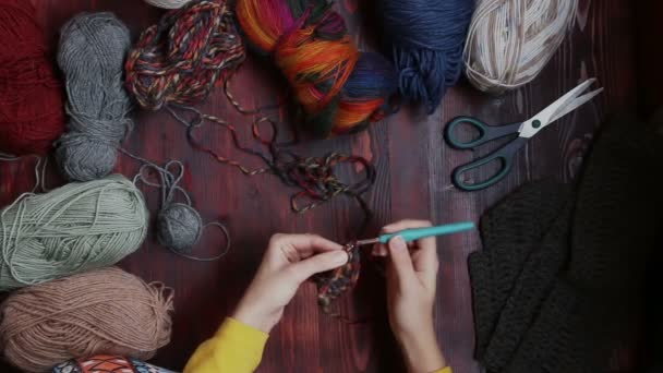 Ovanifrån av ung kvinna händer på träbord runt garn stickning snood — Stockvideo