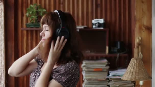 Середній знімок білої жінки, що слухає музику і танцює в навушниках вдома — стокове відео