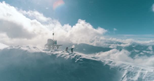 Luchtfoto van twee skiërs cross de bergrug door de wolken — Stockvideo