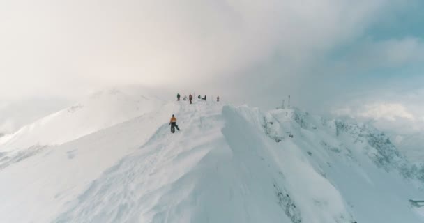 Vista aérea dos esquiadores e pronto para atravessar o cume da montanha através das nuvens — Vídeo de Stock
