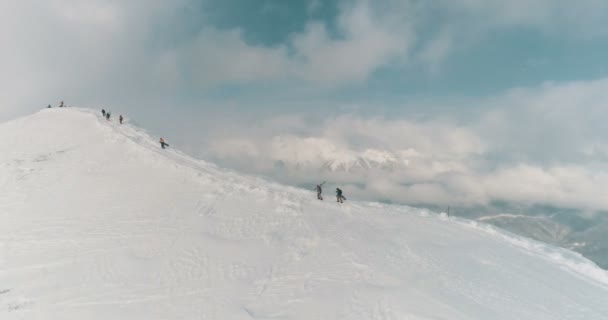 Αεροφωτογραφία του σκιέρ και έτοιμοι να διασχίσουν την κορυφογραμμή του βουνού μέσα από τα σύννεφα — Αρχείο Βίντεο