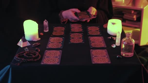 Mittlere Aufnahme einer hexenhaften Hand, die Taro-Karte auf den Schreibtisch legt, während das Vermögen buchstabiert wird — Stockvideo