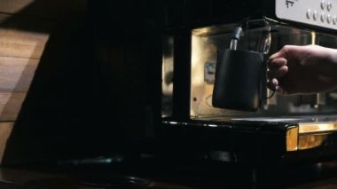 Kahve makinesinin buharı altında, orta derecede, el sıkışın.