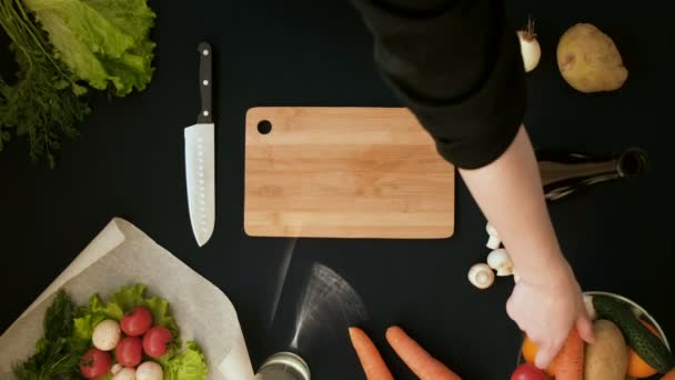 Vista superior de la joven cortando verduras en tablero de madera — Vídeo de stock