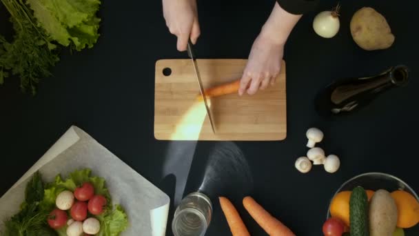 Top pohled rukojeti záběr mladé ženy řezání čerstvé zeleniny na dřevěné desce — Stock video