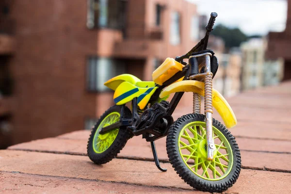 Mini Motocross Bike Toy green and yellow with building Background