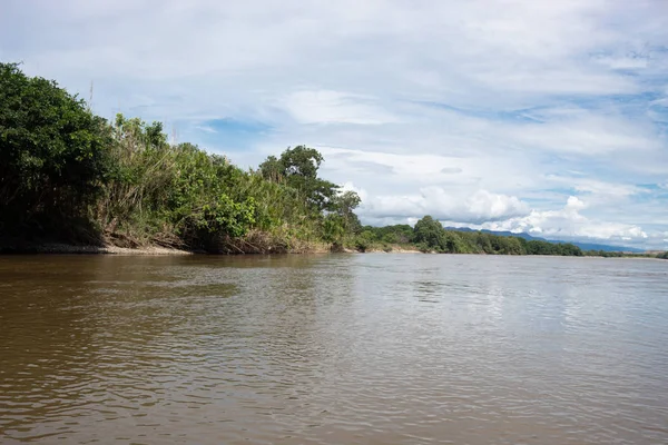 Magdalena River in sunny day with green trees and bushes, clouds and blue sky at background near to Aipe town, Huila Colombia
