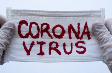 Beyaz Yüz Maskesi 'ne kırmızı Coronavirus yazısıyla ve iki eli beyaz eldiven ya da onları tutan Esterilize kürelerle kapatılmış. Covid 2019