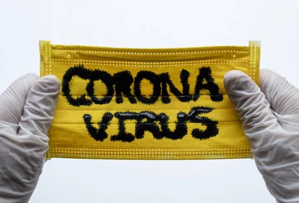 コロナウイルスの碑文と白手袋や滅菌グローブで2つの手でそれらを保持して黄色の顔マスクまで閉じます Covid 2019 — ストック写真