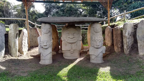 İki tarafı da Kolombiya San Agustin arkeoloji parkında iki savaşçıyla birlikte bir insan ocağı tutan bir rahip ya da şamanla birlikte antik bir dolmen. Antik kolomb öncesi kültür. 