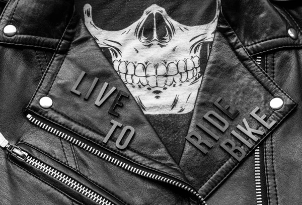 closeup to live to ride bike lettering over biker leather jacket and skull kerchief. motorcycle style, black and white photography