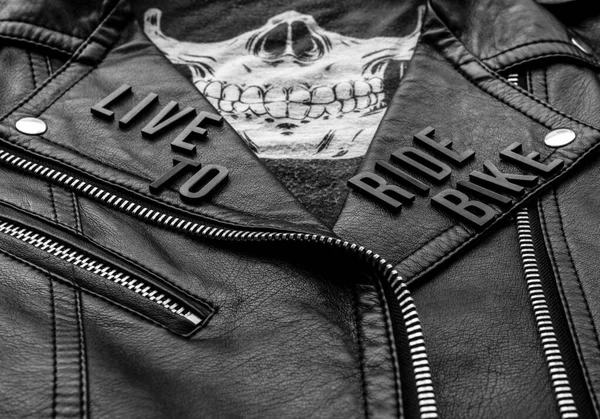 closeup to live to ride bike lettering over biker leather jacket and skull kerchief. motorcycle style, black and white photography