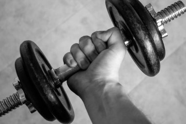 Erkek eli, eski bir demir dambılı sıkıyor. Fitness, spor, sağlıklı yaşam, spor ve ev antrenmanı için ideal. siyah ve beyaz fotoğrafçılık