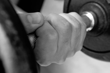 Demir 5 dambılını erkek elinin sıkmasına yakın. Fitness, spor, sağlıklı yaşam, spor ve ev antrenmanı için ideal. Siyah beyaz fotoğraf.