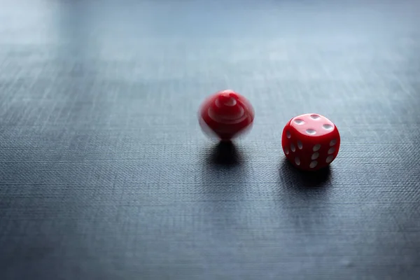 Closeup to a red dices, one dice is spinning over a black background. Ideal fo gamble, board games and bets