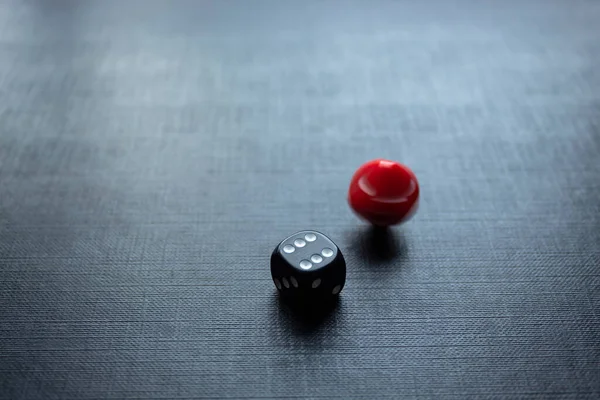 Closeup to a dices, one dice is red and one black dice is spinning over a black background. Ideal for gamble, board games and bets