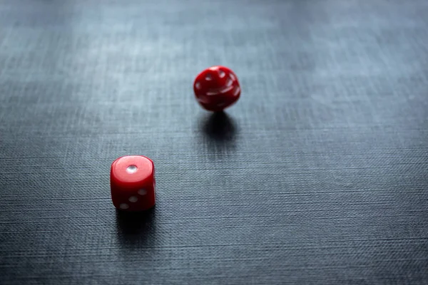 Closeup to a red dices, one dice is spinning over a black background. Ideal fo gamble, board games and bets