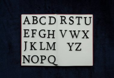 ALPHABET 'e yakın, mavi donanma arka planında boş defter üzerine yazılmış. Okuma ve konsept fotoğrafçılık eğitimi