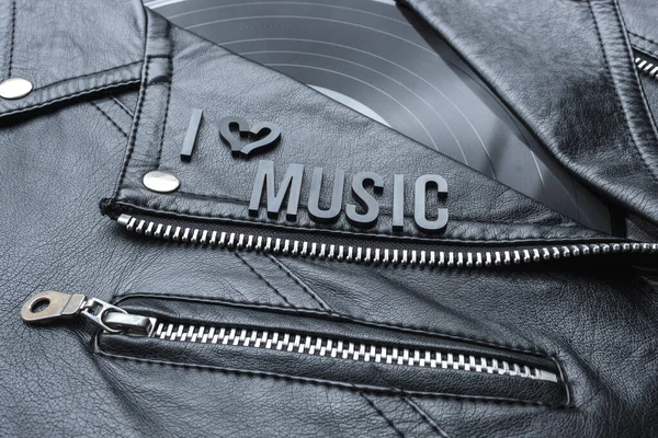 Closeup to a I hearth (love) music lettering art over a black leather biker jacket with LP vinyl disc. Music lover concept, retro photography.