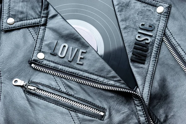 Closeup to a love music lettering art over a black leather biker jacket with LP vinyl disc. Music lover concept, retro photography.