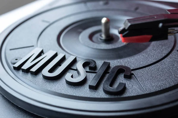 Close up to a MUSIC lettering word over a black turntable and a red turntable needle. Music lover concept
