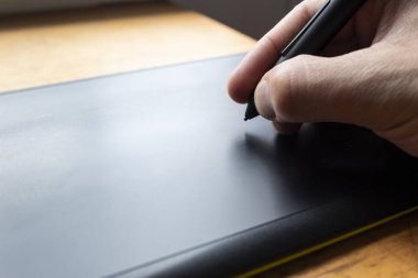 Siyah ve yeşil çizim tabletinin üzerine siyah dijital bir kalem tutan bir erkeğe yakın. Grafik tasarımı, ağ ve teknolojiyle ilgili her şey için ideal