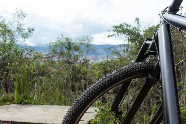 City landscape at the top of mountain view with green vegetation and black mountain bike front, handle bar and front tire